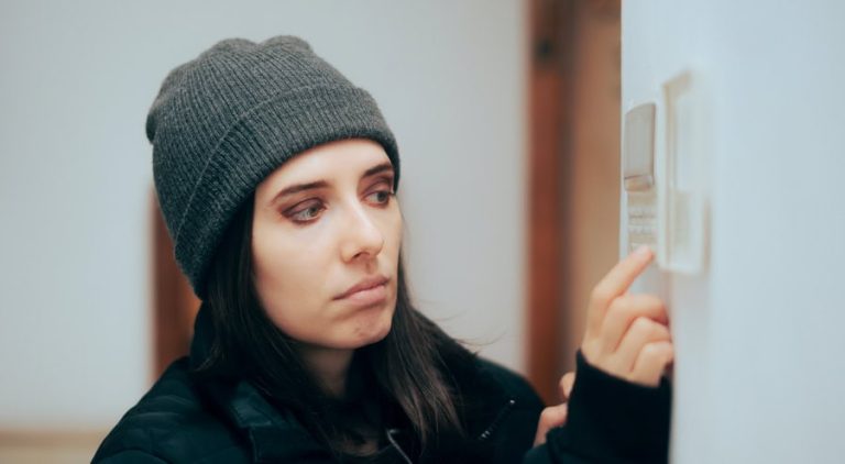 Person adjusting their thermostat in an effort to get the furnace to turn on.