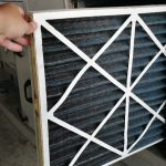 Person changing the air filter for an AC unit.