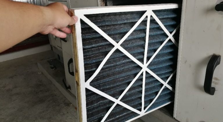 Person changing the air filter for an AC unit.