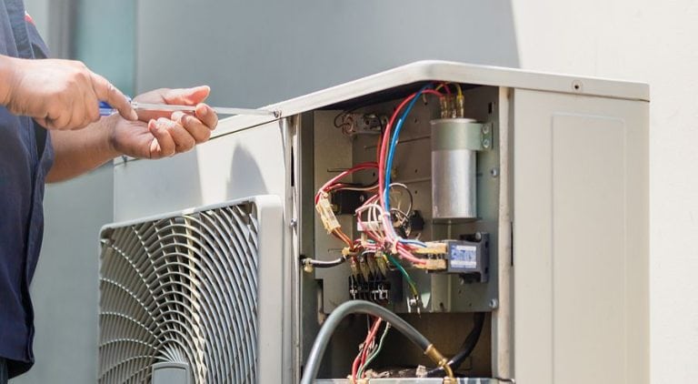 Technician working on an open air conditioning unit.