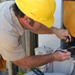 An AC repairman helps maintain an air conditioning unit.